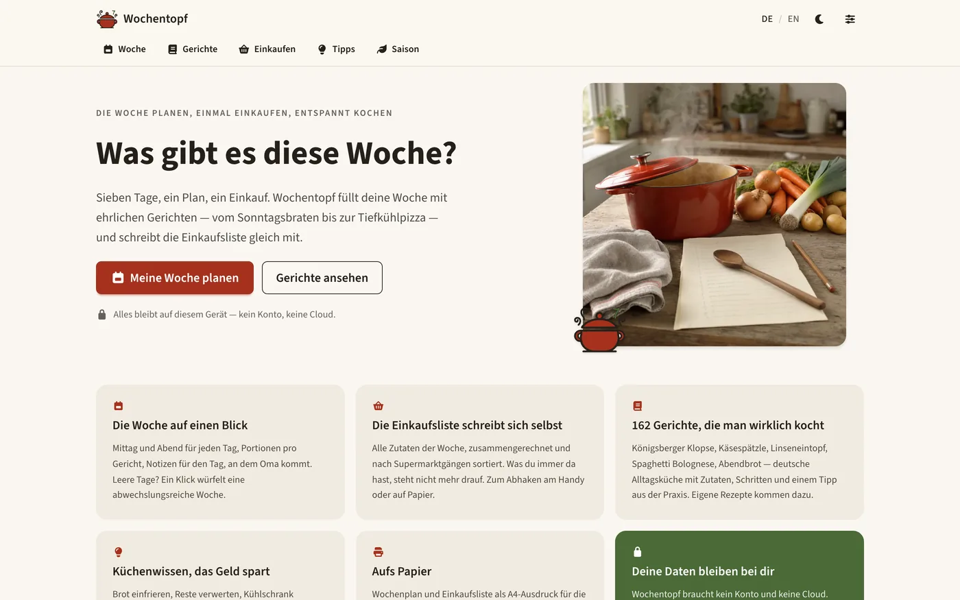 Startseite von Wochentopf: Kopfleiste mit den Reitern Woche, Gerichte, Einkaufen, Tipps und Saison, daneben die Überschrift „Was gibt es diese Woche?“ mit den Knöpfen „Meine Woche planen“ und „Gerichte ansehen“ und dem Hinweis, dass alles auf diesem Gerät bleibt. Rechts ein Foto von einem roten Emailletopf auf einem Holztisch mit Möhren, Zwiebeln, Lauch, Holzlöffel und leerem Notizblock. Darunter sechs Karten: die Woche auf einen Blick, eine Einkaufsliste, die sich selbst schreibt, 162 Gerichte, die man wirklich kocht, Küchenwissen, aufs Papier, und deine Daten bleiben bei dir.